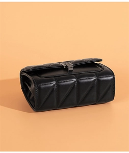 Detailed view of the black quilted geometric texture and dark metal clasp on this handbag