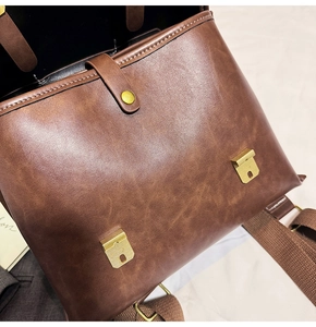 Detail view of brown vintage leather backpack with antique brass buckle and canvas strap