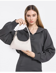 Minimalist creamy white leather underarm bag shown on a model in a casual grey hoodie