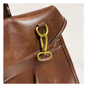 Detail of dark brown leather texture with golden metal hook and contrast stitching