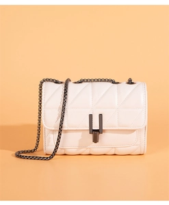Detail of cream quilted crossbody bag with metal chain strap and geometric H-shaped lock