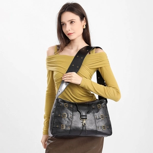 Retro black leather tote bag with wide shoulder strap and antique metal buckles on model