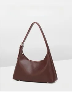 Detail view of smooth leather underarm bag in deep brown with silver hardware and buckle