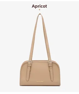 Detail view of apricot faux leather shoulder bag with decorative straps and silver buckles