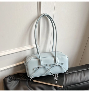 Détail du sac en cuir brillant bleu clair avec nœuds sur un canapé vintage
