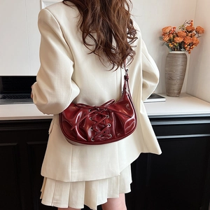 Detail shot of a dark red patent leather hobo bag with corset-style lace-up design