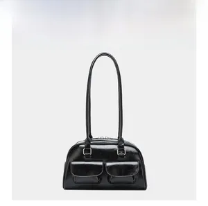 Detail view of black oily leather handbag with front flap pockets and silver buckles
