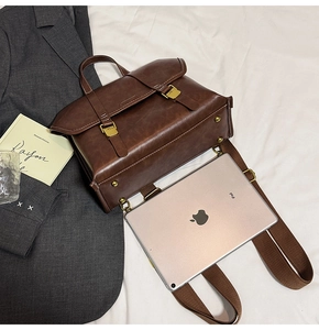 Close-up of vintage dark brown leather backpack with buckle straps on a soft white bed
