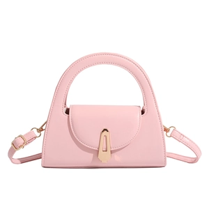 Detail of pink semi-circle handbag featuring golden geometric clasp and smooth leather