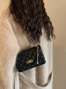 Détail d'un sac bandoulière matelassé en cuir noir avec chaîne dorée et fermoir métallique
