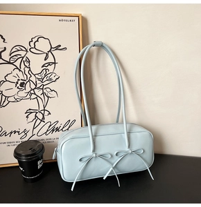 Détail d'un sac Boston bleu clair avec nœuds délicats et fines bretelles doubles