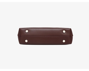Detail of dark burgundy leather bag base with silver studs and precision stitching