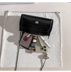Dettaglio interno della borsa nera a coccodrillo con spazio e catena metallica