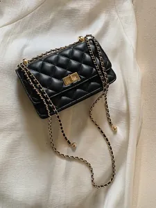 Détail d'un sac bandoulière noir matelassé avec fermoir rotatif doré et bandoulière