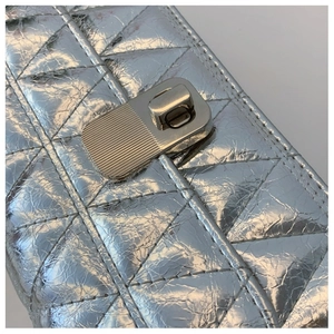 Macro shot of silver quilted faux leather texture with a metallic rotary lock detail