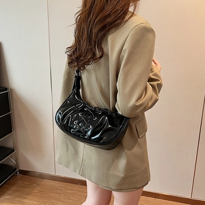Detail of black patent leather shoulder bag with lace-up straps and high-gloss finish