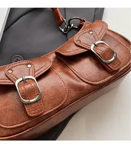 Close-up of brown embossed leather shoulder bag with vintage silver metal buckles