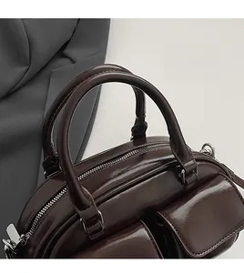 Detailed close-up of dark brown leather handbag with round handles and silver zipper