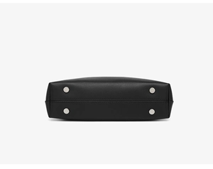 Detail view of the black leather bag bottom with four silver metal feet and precise stitching
