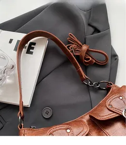 Detail of vintage brown textured leather hobo bag with sleek strap and metal rivets