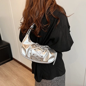 Detail of silver metallic hobo bag with trendy lace-up bow and chic crescent shape design