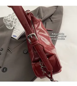 Detail der verstellbaren silbernen Metallschnalle an einer weinroten Lackleder-Schultertasche