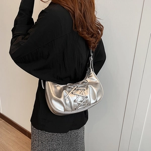 Silver metallic pleated bag detail with bow straps shown on a shoulder in a lifestyle shot