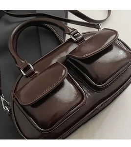 Detail of dark brown wax leather bag showing stitching and silver metal buckle hardware