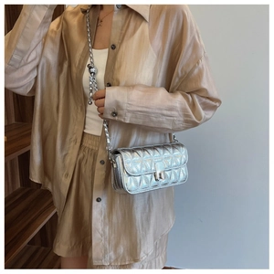 Detail of silver metallic quilted bag featuring a turn-lock closure and knotted chain strap
