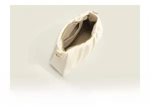 Detailed interior of a pleated cream white dumpling bag with soft fabric lining and golden zip