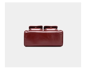 Detail view of burgundy oil-waxed leather shoulder bag with two flip-cover pockets