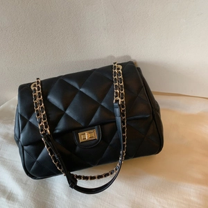 Classic black quilted shoulder bag with gold chain strap and metal lock in high texture