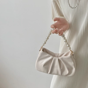Detail view of cream pleated cloud bag with elegant large pearl handle and metal hooks