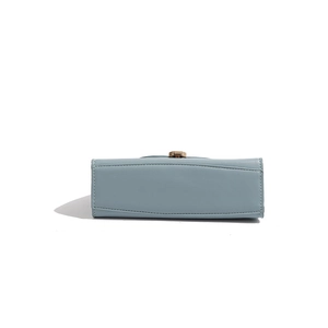 Detail view showing smooth base and gold buckle on a light blue semicircular leather bag