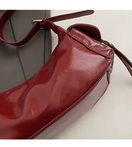 Nahaufnahme der burgunderroten Lackledertasche mit feinen Nähten und verstellbarem Riemen