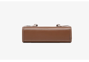 Close-up of brown leather bag bottom with contrast white stitching and premium texture