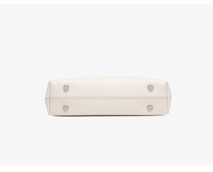 Detail shot of cream leather bag base with silver-tone metal feet and precision stitching