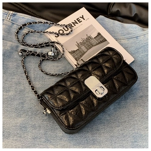 Detail of black quilted leather texture with silver chain and rotary metal lock
