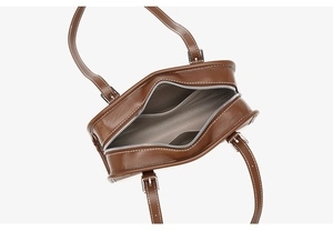 Inside view of brown leather handbag featuring herringbone fabric lining and inner pocket