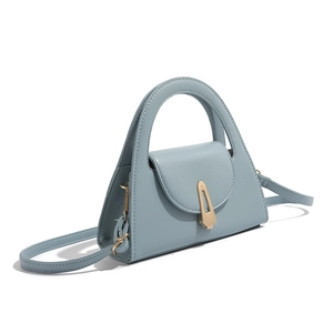 Macro detail of misty blue semicircular handbag with gold clasp and adjustable strap