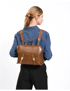 Rear view of model wearing a vintage brown faux leather backpack with metallic buckles