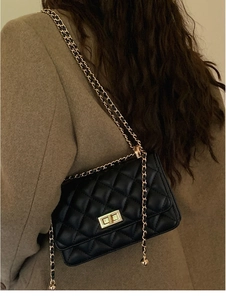 Détail du sac à bandoulière matelassé noir avec chaîne dorée et pendentif en métal