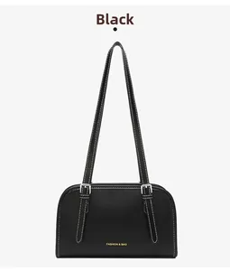 Detail of black minimalist shoulder bag with contrast white stitching and gold lettering