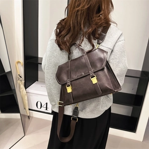 Classic dark brown leather messenger bag with white stitching and golden metal buckles