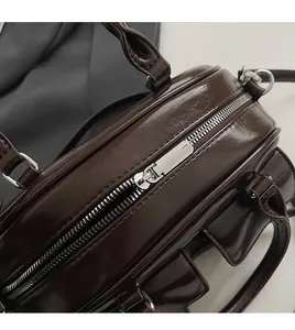 Close-up of smooth silver metal zipper on vintage brown leather boston handbag