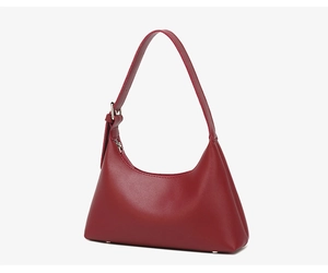 Macro view of burgundy crescent leather bag showing side texture and metal buckle