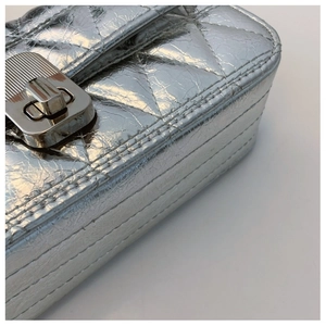 Macro detail of silver rhombic quilted leather bag with metallic clasp and precise stitching