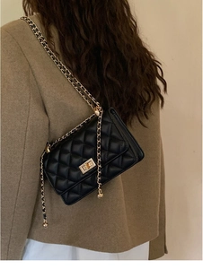 Détail du sac bandoulière noir matelassé avec fermoir doré et bandoulière en chaîne