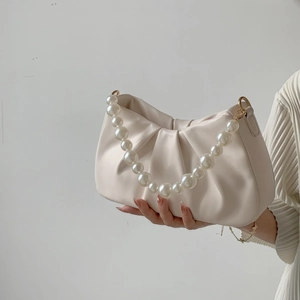Detail of off-white pleated cloud bag featuring large pearl handle and gold metal hardware