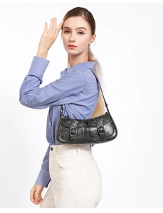 Detail of vintage black biker shoulder bag with silver buckles and Y2K style pockets